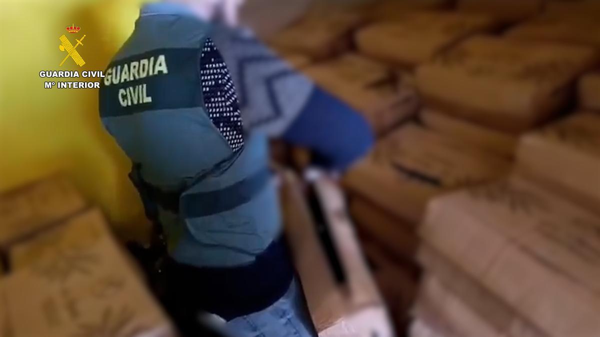 Un agente de la Guardia Civil con parte del aceite recuperado.