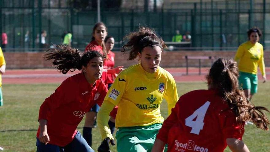 María conduce el balón en presencia de dos rivales del León FF.