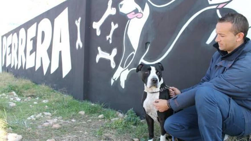 Bautista con una de las mascotas de la perrera junto al mural que da la bienvenida a las instalaciones.