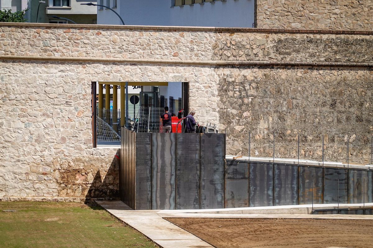 Los operarios ultiman la rampa de acceso por el pórtico que se ha dejado para el paso de peatones tras reconstruir la brecha de la calle Hermanos Merino.