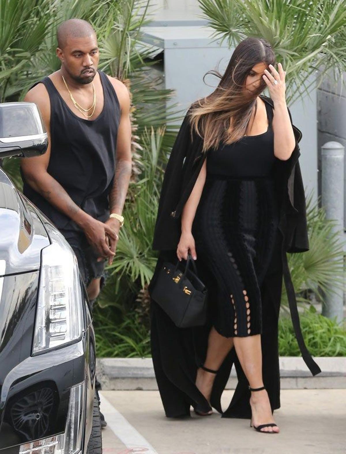 Kim Kardashian con el abrigo echado sobre los hombros y Kanye West, en tirantes