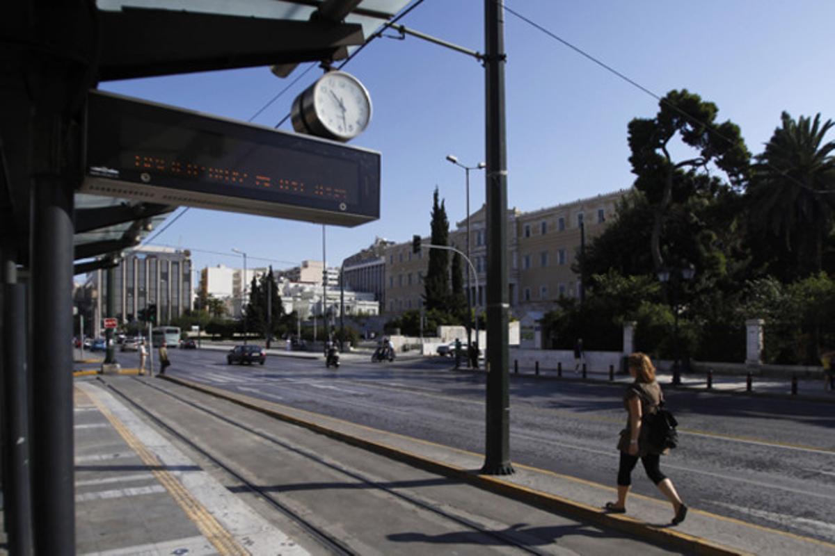 Una dona passa per davant d’una parada de tramvia buida a prop del Parlament grec, al centre d’Atenes. Els sindicats han tornat a convocar una vaga de transport públic en protesta contra les retallades del Govern.