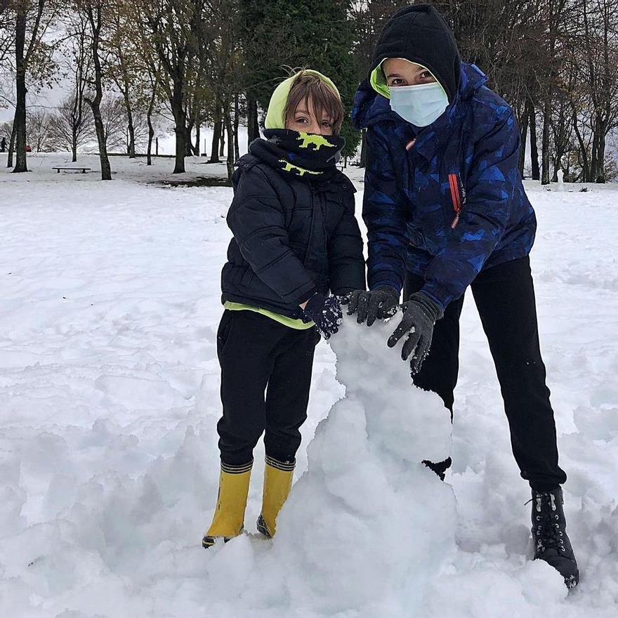 Adrián y Gabriel García preparan su muñeco de nieve en el campo de San Roque, en Tineo. | D. Álvarez 