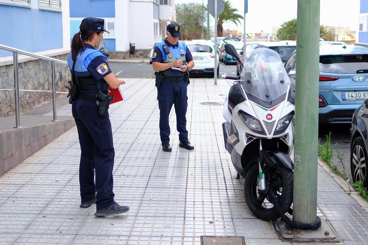 Un policía local toma los datos de una moto mal aparcada.