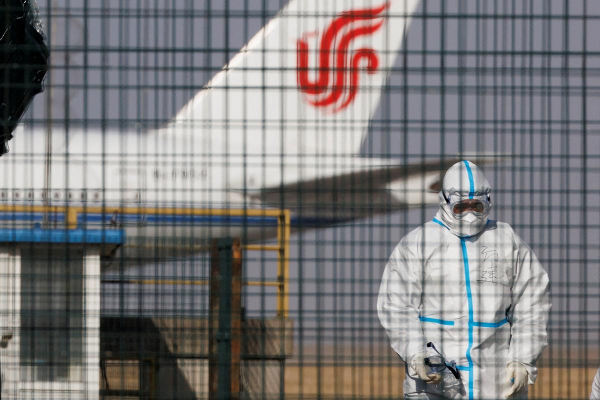 Un trabajador con traje protector camina cerca de un avión de las aerolíneas Air China en el Aeropuerto Internacional de Beijing.
