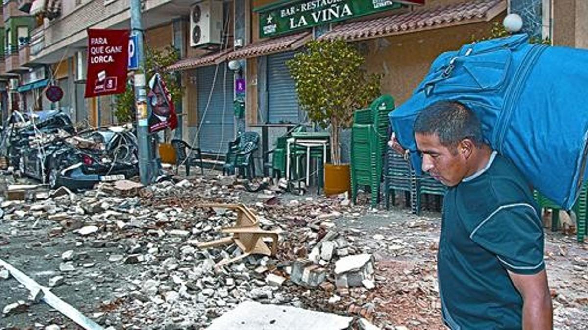 Un hombre con un petate pasa, ayer, por delante del bar La Viña, donde una persona murió como consecuencia del terremoto.