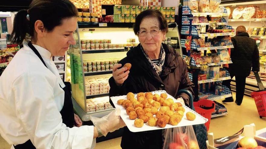 Una alumna de la Escuela de Hostelería ofrece croquetas a una clienta de la plaza de Sama.