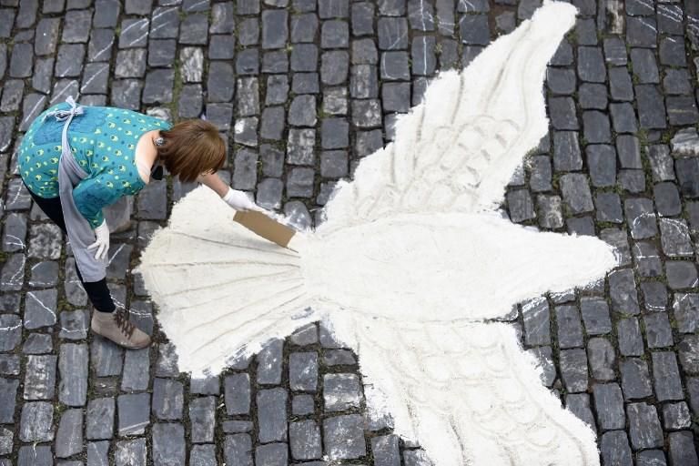 Una mujer dibujando con arena para la procesión del Corpus Christi en Brasil / AFP PHOTO / DOUGLAS MAGNO