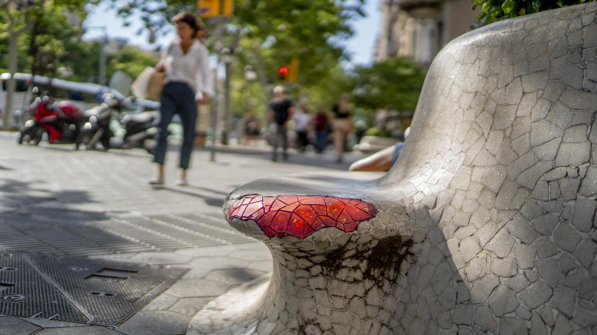 Una de las coloridas &quot;tiritas&quot; de Juncosa tapa un agujero del trencadís en un banco del paseo de Gràcia.