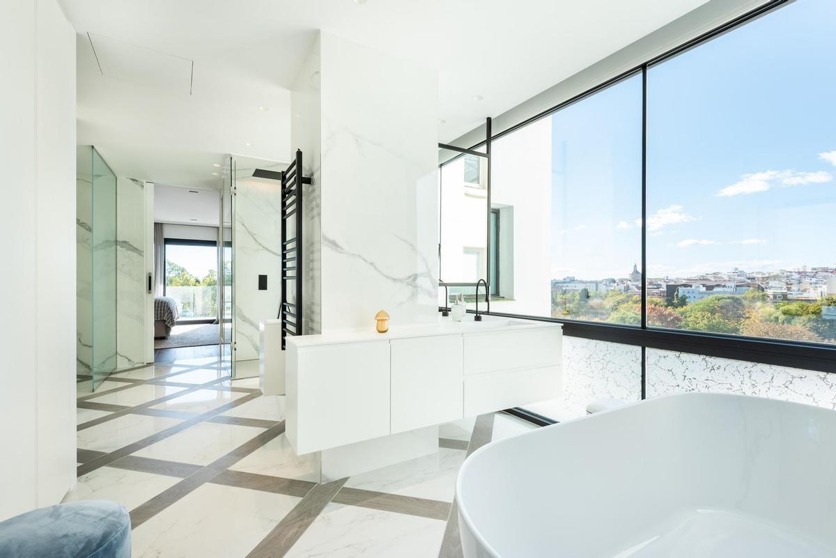 El baño del dormitorio principal, con unas impresionantes vistas, está regado por la luz natural. Cuenta con ducha y bañera, y suelos y paramentos en mármol de la mejor calidad.