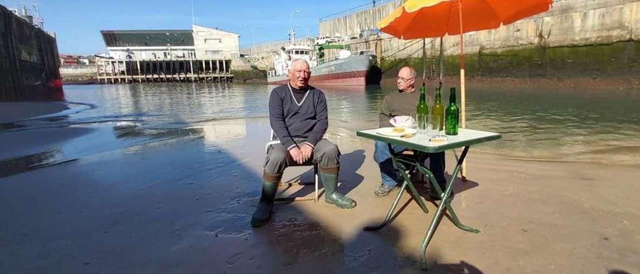 Ángel Suárez y Pepín del Rosal, sentados con el aperitivo en la dársena interior del puerto de Llanes.