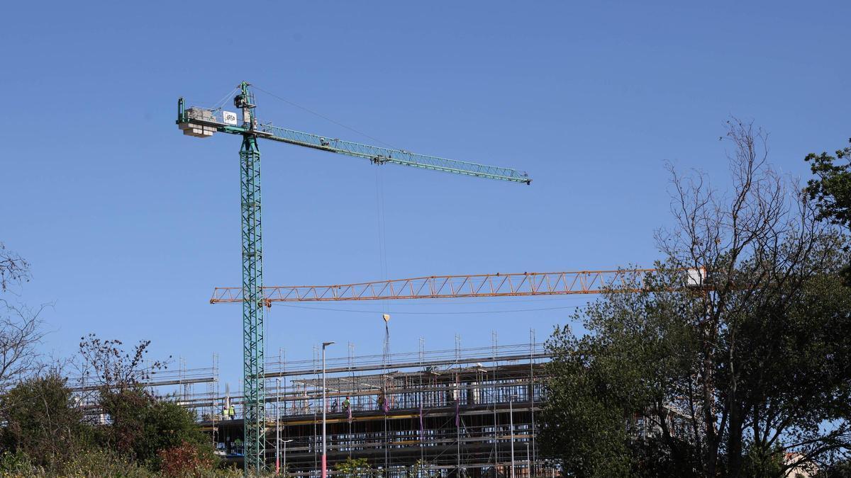 Grúas trabajando en la construcción de un edificio de viviendas en Navia.