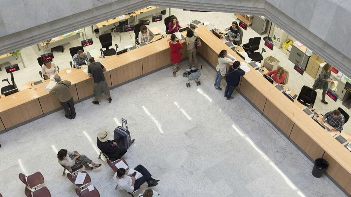 Varios ciudadanos esperan su turno en un edificio administrativo.