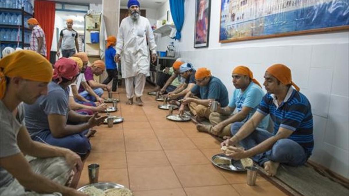 Comensales en el interior del Sikh Gurudwara Gurdarshan Sahib Ji, el templo sij de la calle Hospital, en Barcelona.