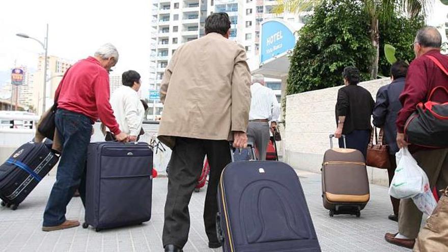 Un grupo de turistas del Imserso se dispone a entrar en un hotel de Benidorm tras llegar en autobús