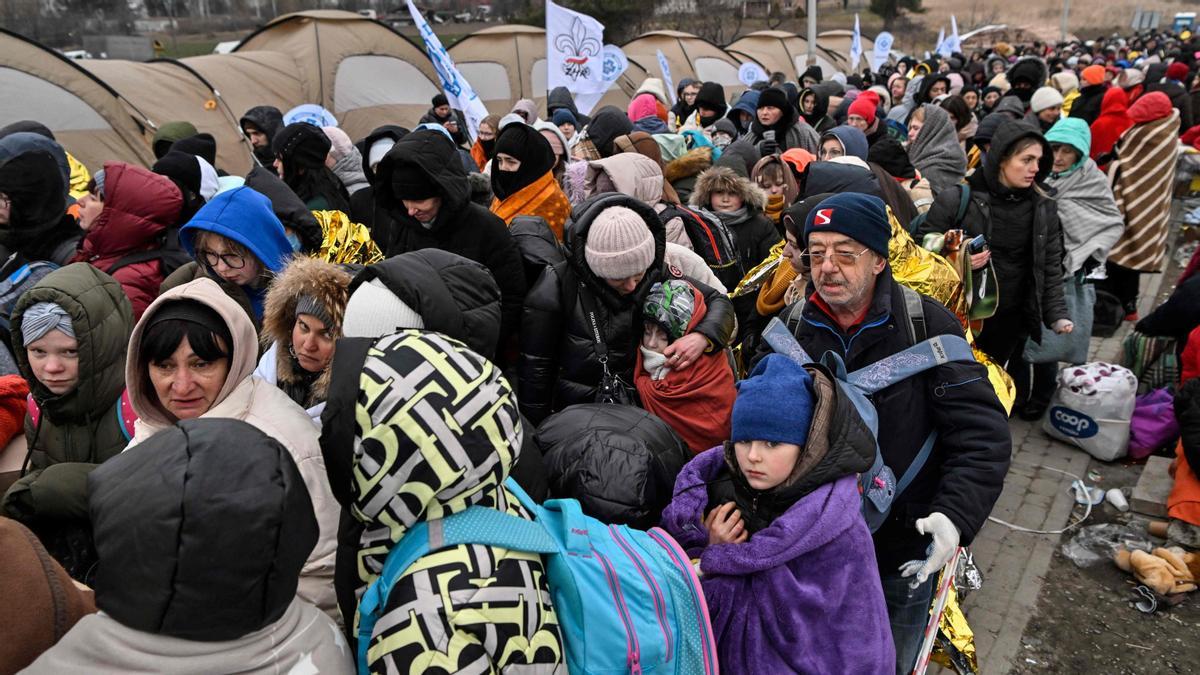 Los refugiados hacen cola en el frío mientras esperan ser trasladados a una estación de tren después de cruzar la frontera de Ucrania hacia Polonia, en el cruce fronterizo de Medyka en Polonia