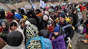 Los refugiados hacen cola en el frío mientras esperan ser trasladados a una estación de tren después de cruzar la frontera de Ucrania hacia Polonia, en el cruce fronterizo de Medyka en Polonia