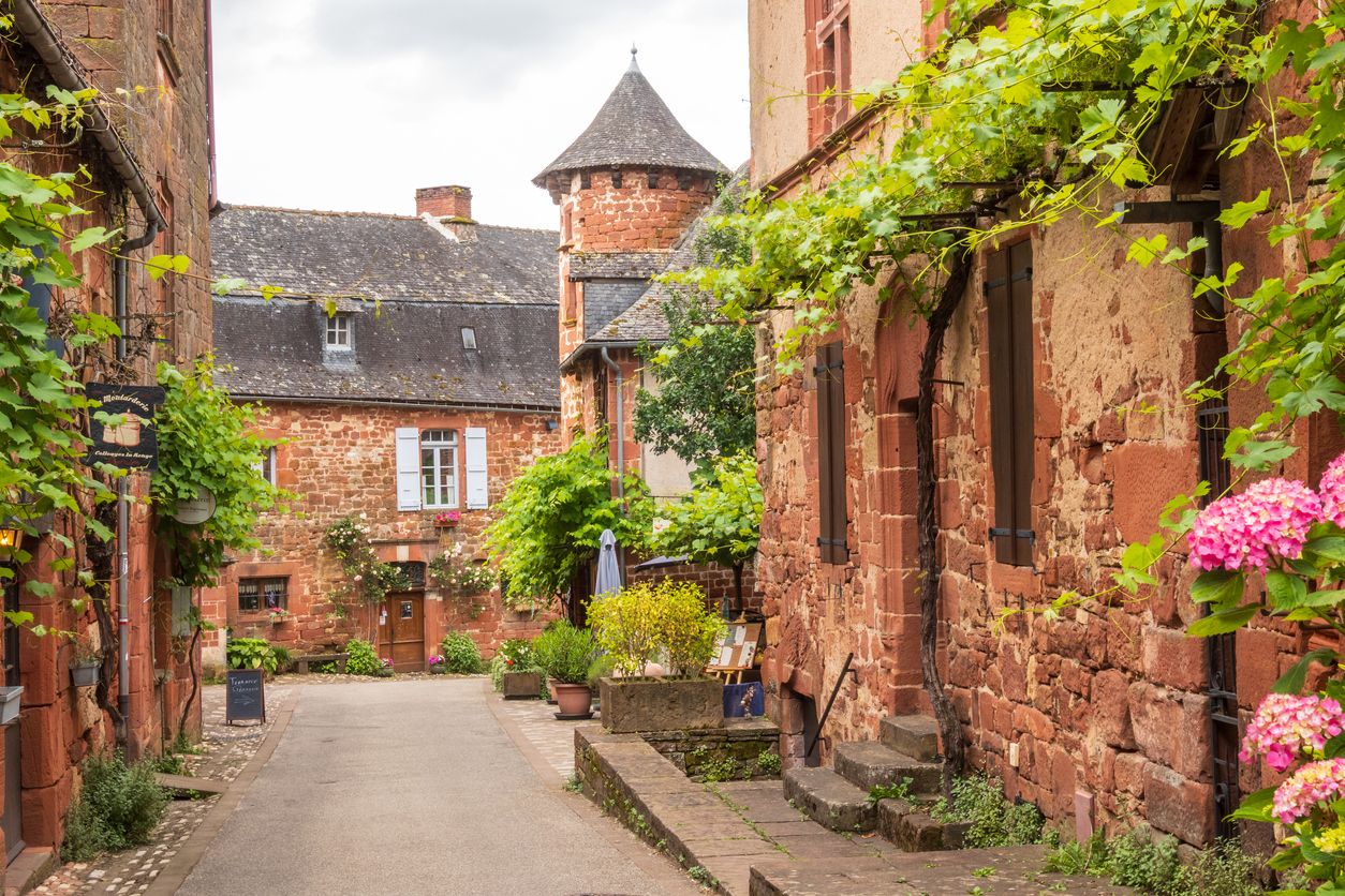 Casas rojas y plantas verdes vistas desde la calle en Collonges-la-Rouge en Francia, Corrèze