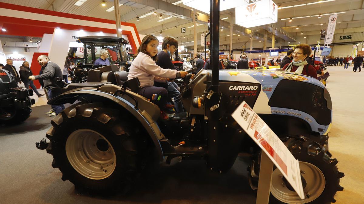 Unos niños trastean en un tractor en uno de los expositores.