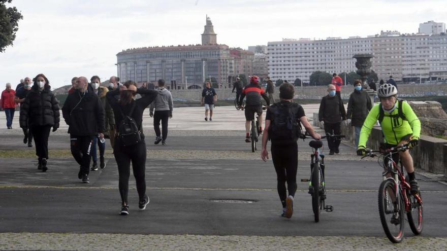 Viandantes protegidos con mascarillas en el paseo marítimo de A Coruña.