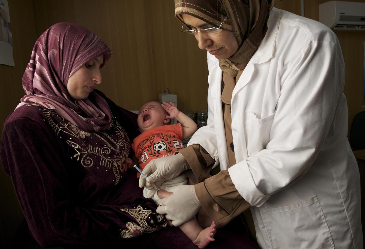 Una enfermera suministra una vacuna a un bebé sostenido por su madre, en una imagen de archivo.