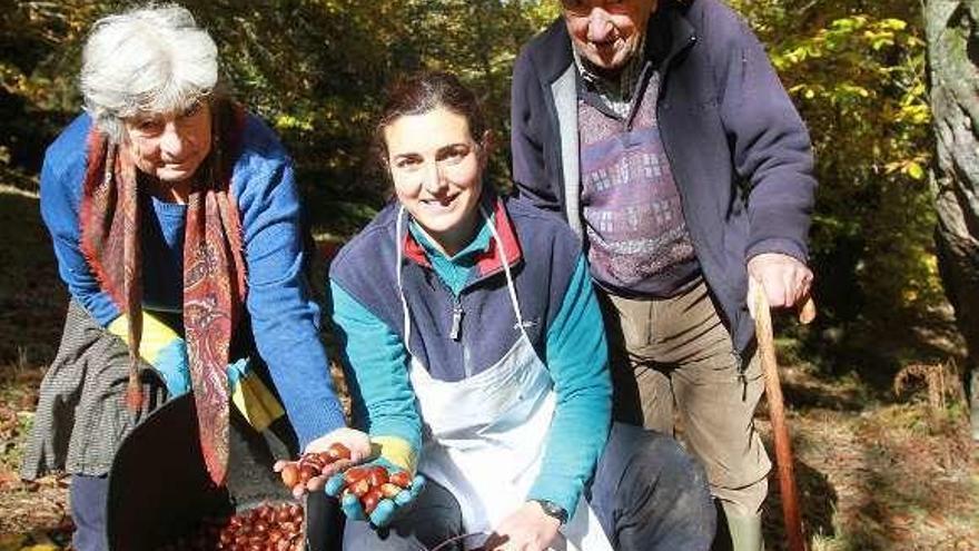 Lina García, centro, con dos vecinos recogiendo castañas.