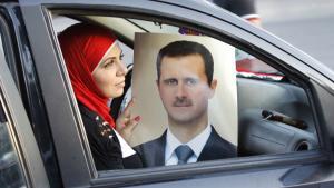 Una mujer muestra el retrato de Bashar a-Asad en una celebración del aniversario del presidente sirio, en Damasco, en el 2013.