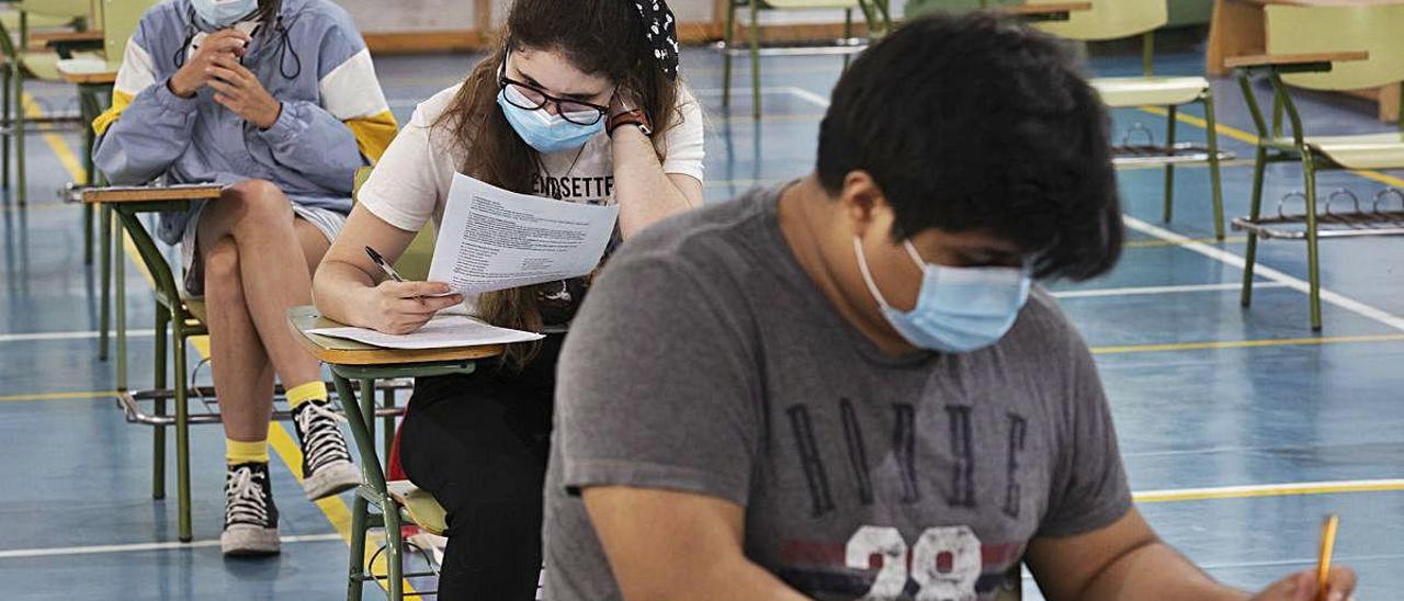 Tres estudiantes realizan un examen con las medidas de protección y distancia social, a final de curso, en València.