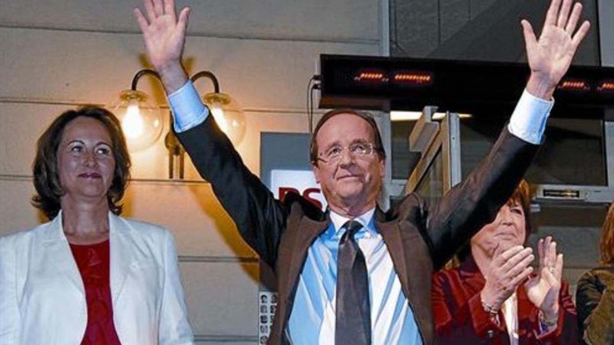 Hollande alza victorioso los brazos entre Ségolène Royal y Martine Aubry (de rojo), ayer.