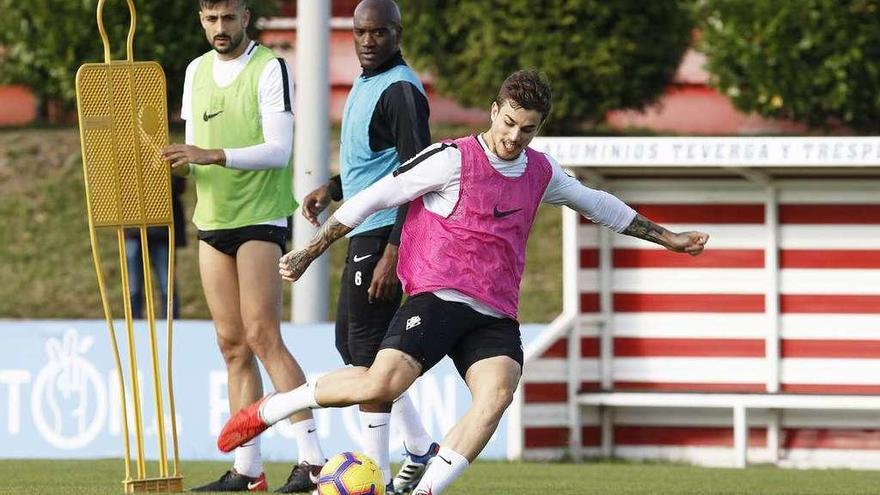 Isma Cerro chuta un balón durante un ejercicio, con Álex Pérez y Babin en segundo término.