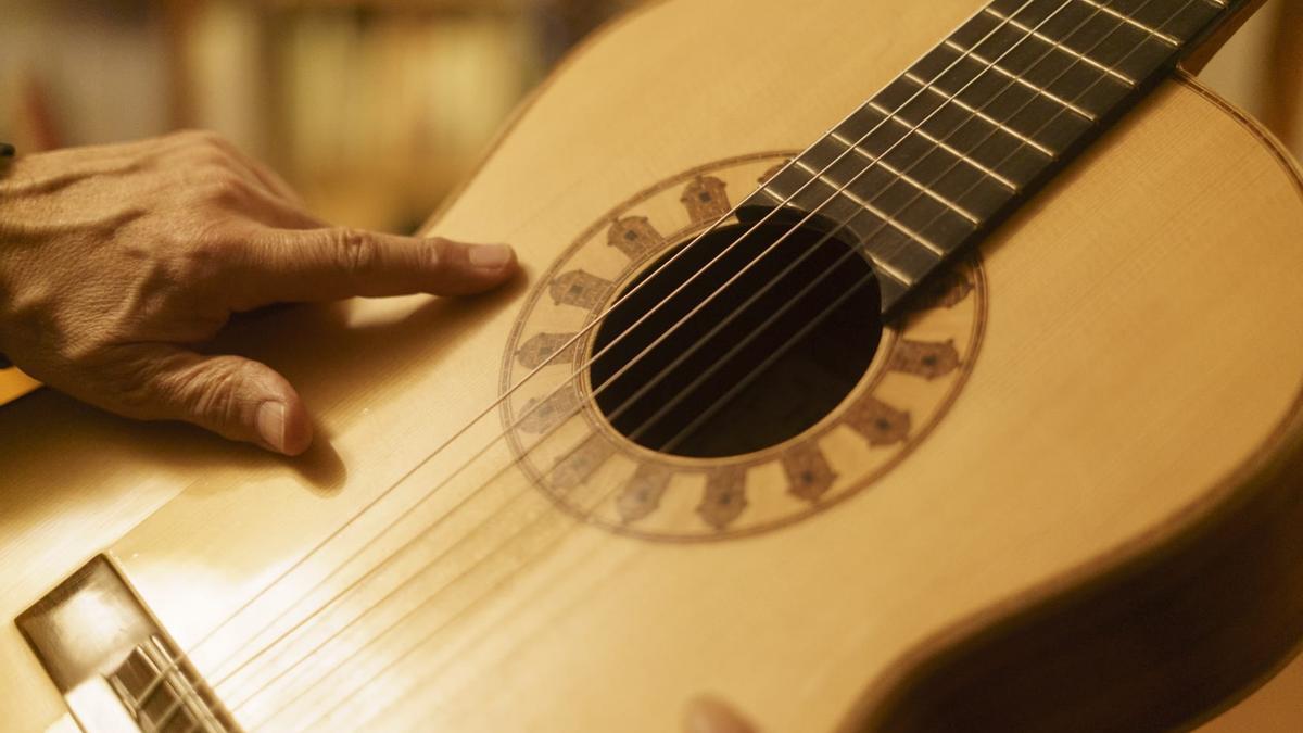 El músico muestra el detalle de la boca de la guitarra.