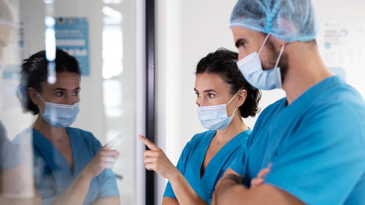 Dos médicos observan a un paciente a través de un cristal.