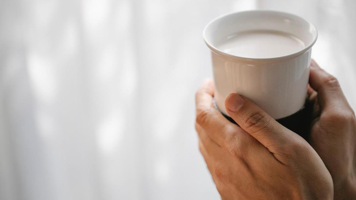 Una persona sostiene una taza de leche.