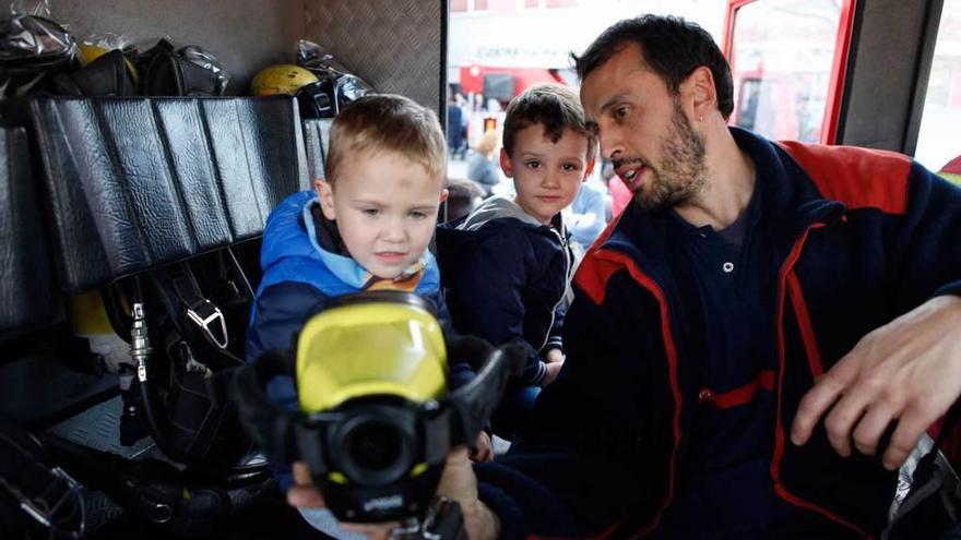 Nicolás Cué -a la izquierda- y Javi Prieto, ambos de 3 años, observan la cámara térmica que les enseña el bombero Iván Nieto.