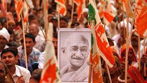 Un granjero sostiene un retrato de Mahatma Gandhi durante una marcha de protesta contra las políticas de industrialización del Gobierno, en Gandhinagar en el estado de Gujarat (India)