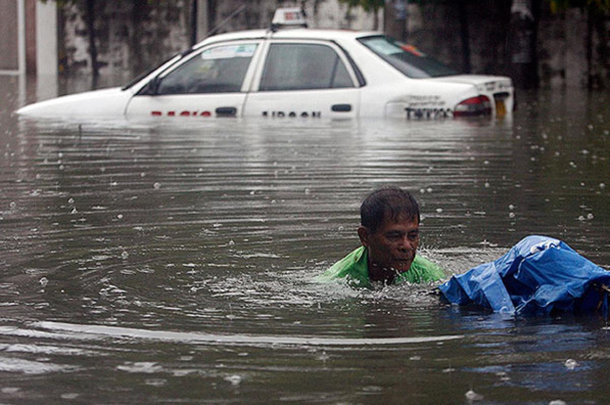 Un membre dels serveis d’emergència desembussa un drenatge després d’un fort aiguat que va inundar una gran part de la ciutat de Quezon, Manila (Filipines).
