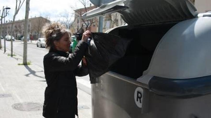 Una ciutadana llançant la brossa al contenidor del rebuig, a Manresa