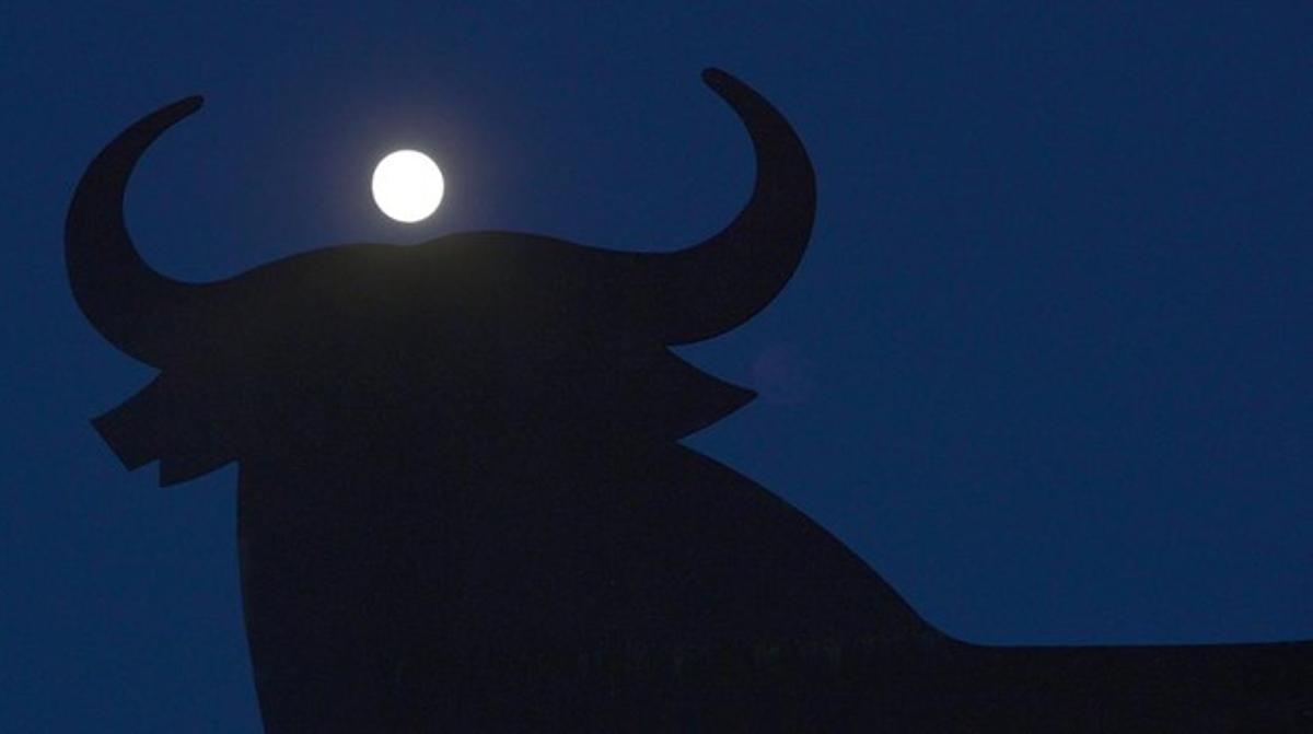 La luna tras la silueta del toro de Osborne en el Puerto de Santa María.