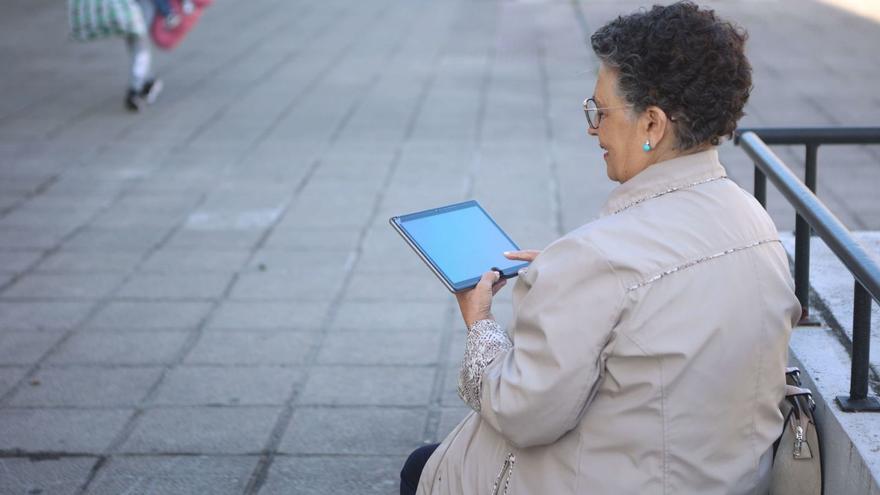 Una mujer maneja un dispositivo electrónico en una calle de A Coruña. | Iago López