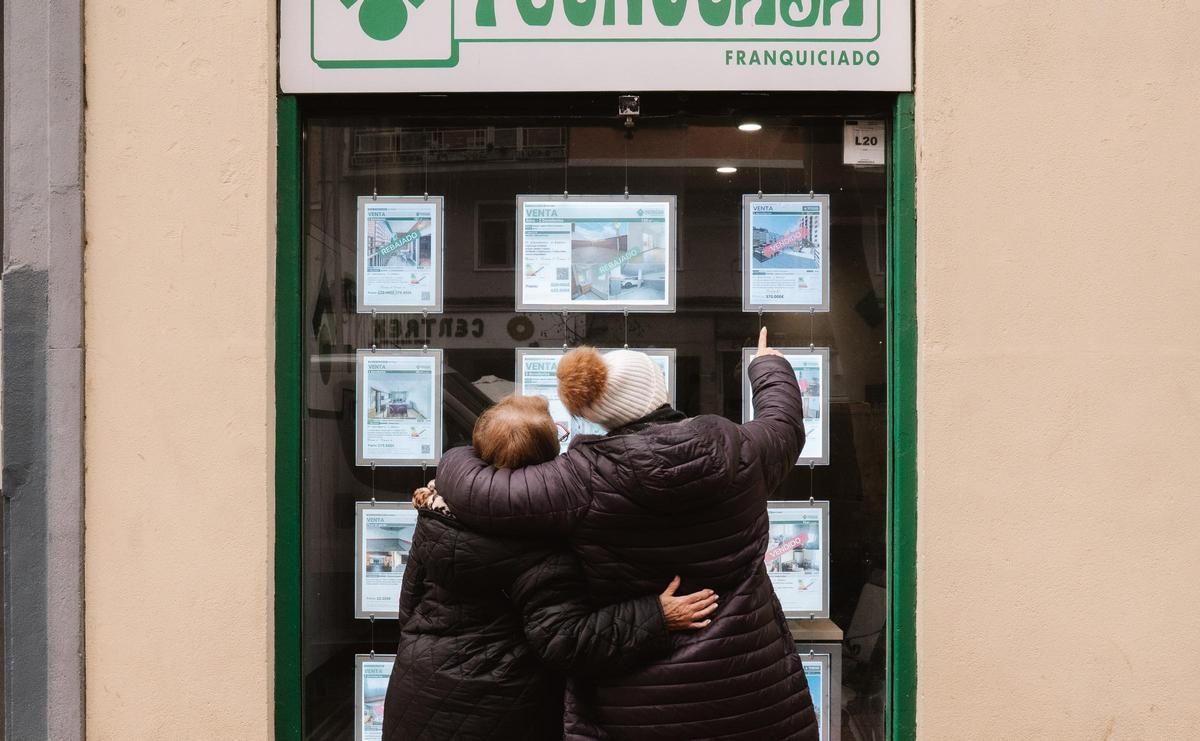 Dos mujeres miran anuncios de pisos en una inmobiliaria.
