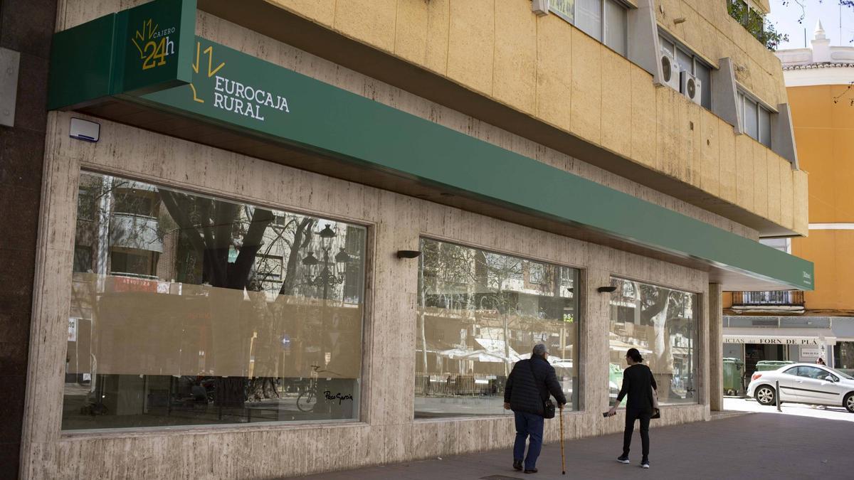 Dos personas pasean ante la fachada de la nueva oficina que Eurocaja Rural abrirá en Xàtiva.