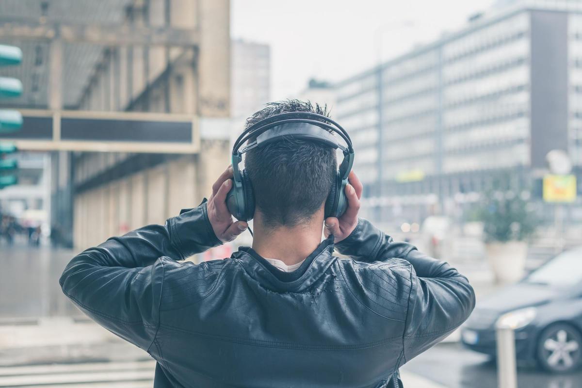 Un joven escucha música con auriculares en la calle.