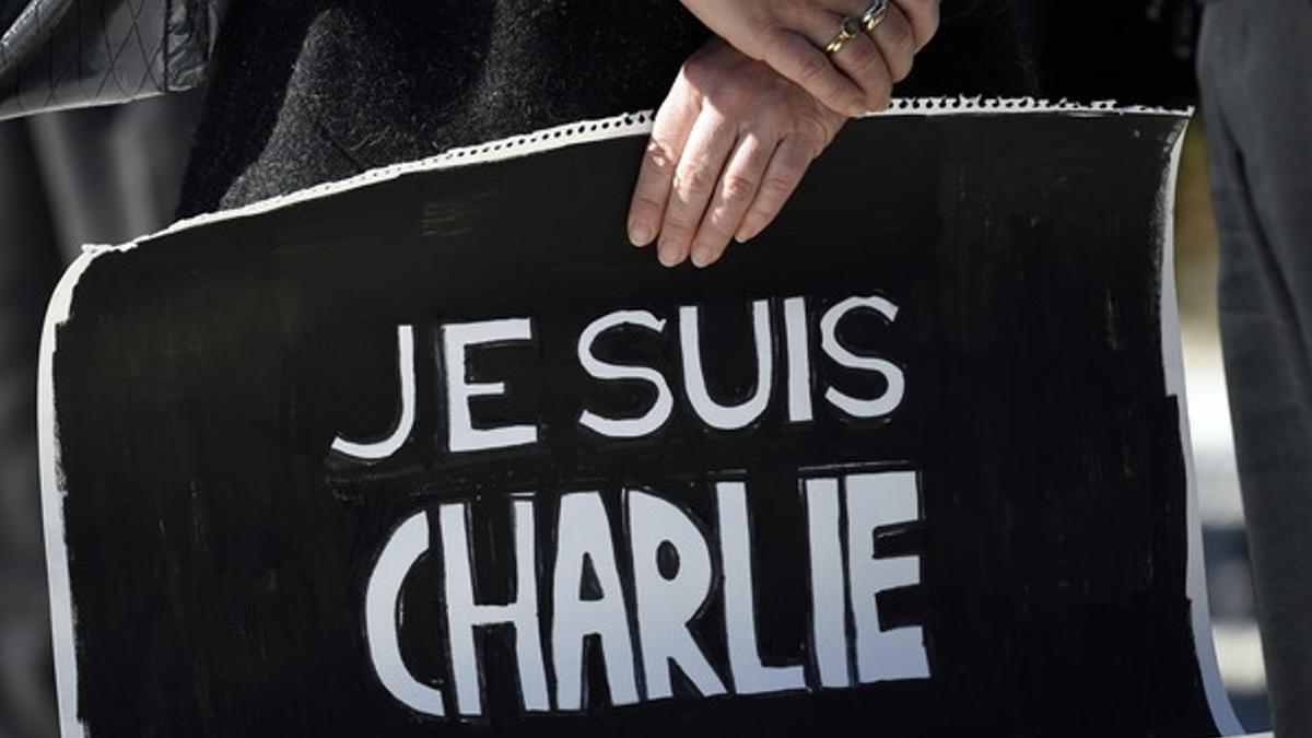 Una mujer sostiene un cartel de apoyo a la revista 'Charlie Hebdo' durante uno de los múltiples homenajes que se celebraron por todo el mundo al día siguiente del atentado en París del pasado día 7.