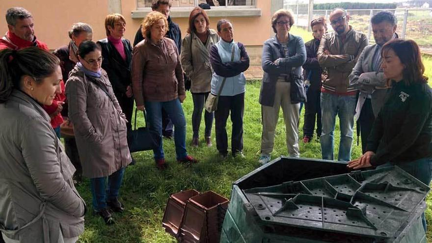 Begoña Honrado, a la derecha, explica a los vecinos el funcionamiento de la compostadora.