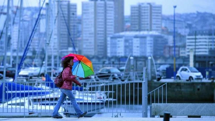 Una mujer se protege de la lluvia en la Marina.