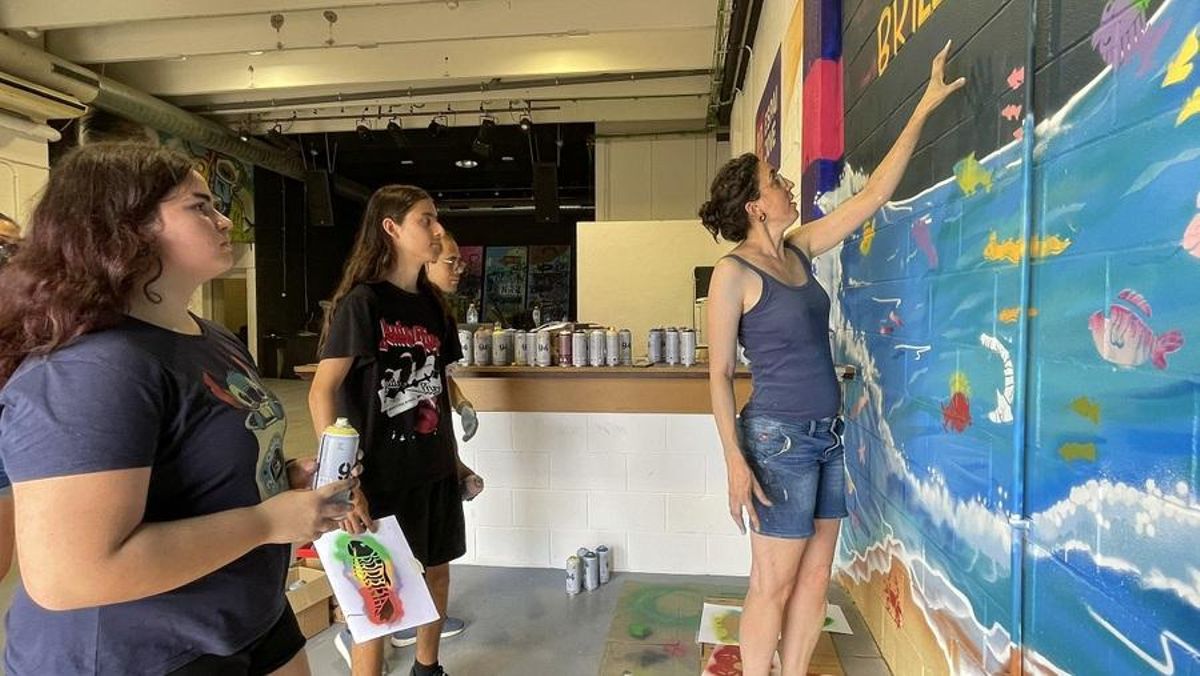Joves pintant el mural.