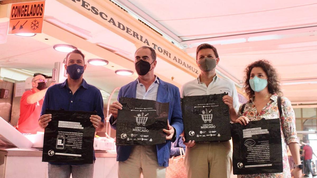 Representantes del Ayuntamiento de Córdoba y de la UCO presentan la iniciativa para entregar bolsas con mensajes divulgativos en los mercados de la ciudad.