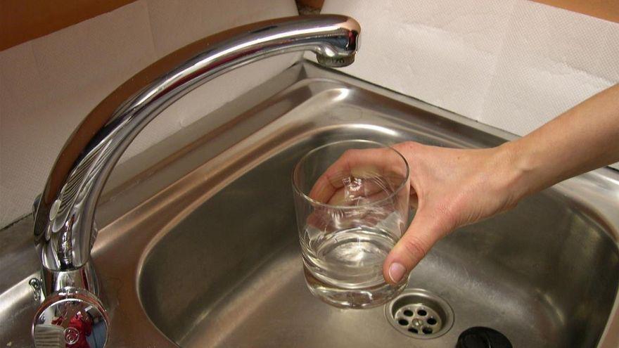 Una persona llena un vaso con agua del grifo.