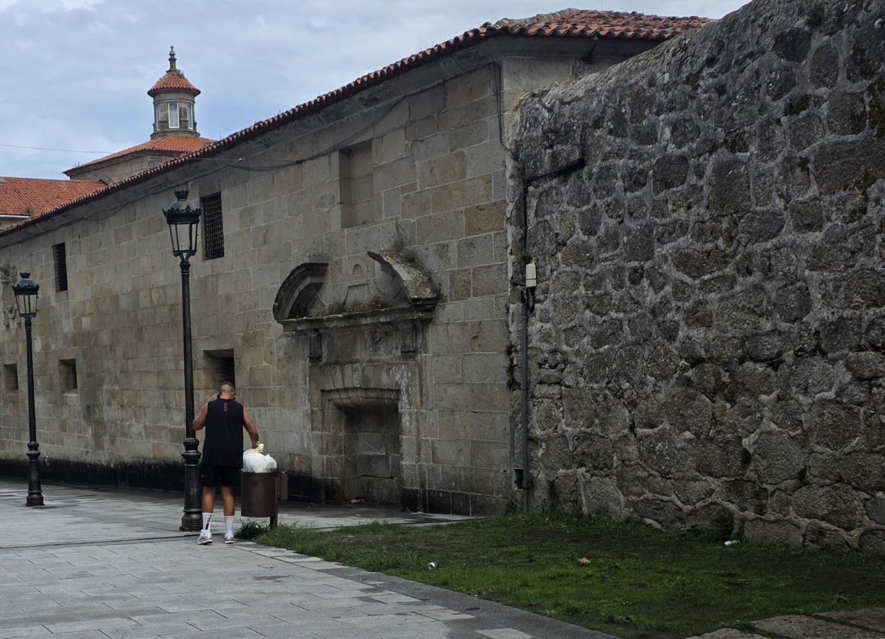 Un hombre tirando una bolsa de basura doméstica en una papelera.
