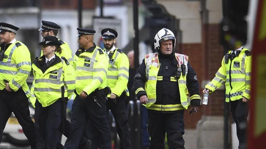 Bomberos y policías caminan junto a Parsons Green.